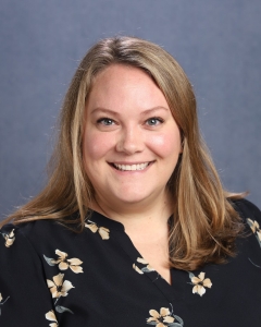 A woman with long blonde hair and black patterned shirt