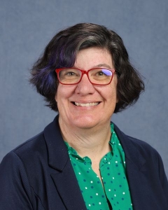 A woman with short dark hair and red glasses