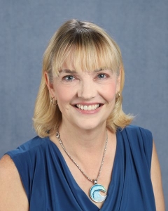 a woman with mid-length blonde hair and a blue tank top