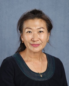 A woman with dark hair tied back and a dark shirt