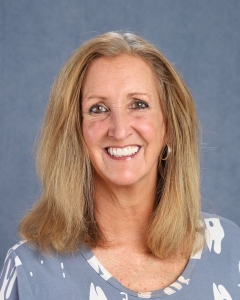 A woman with shoulder length blonde hair and blue floral shirt