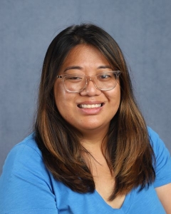 A woman with dark hair, glasses, and a blue shirt