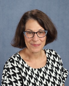 A woman with short dark hair, glasses, and a patterned shirt