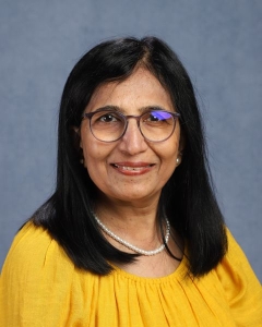 A woman with shoulder length dark hair, glasses, and yellow shirt