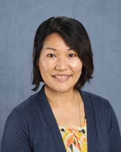 A woman with short dark hair and blue cardigan