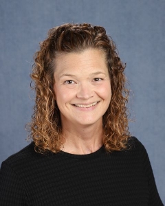 A woman with curly brown hair and black shirt