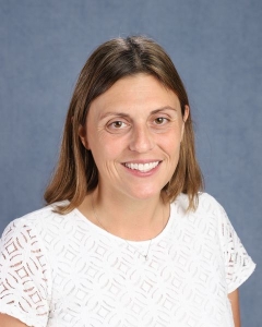 A woman with long brown hair and white shirt