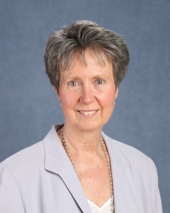 A woman with short grey hair and lavender jacket